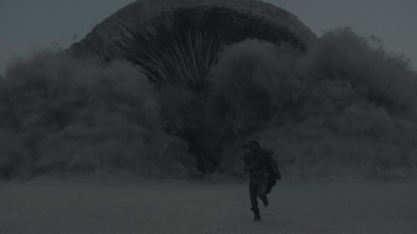 Paul Atreides runs from a gigantic sandworm in 2021's 'Dune' movie.