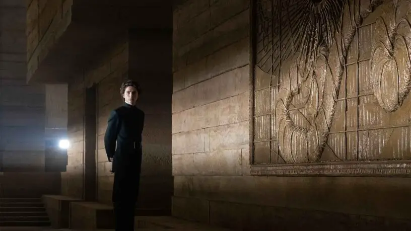 Timothée Chalamet, playing Paul Atreides, stands in front of the sandworm mural, during production of the 'Dune' movie.