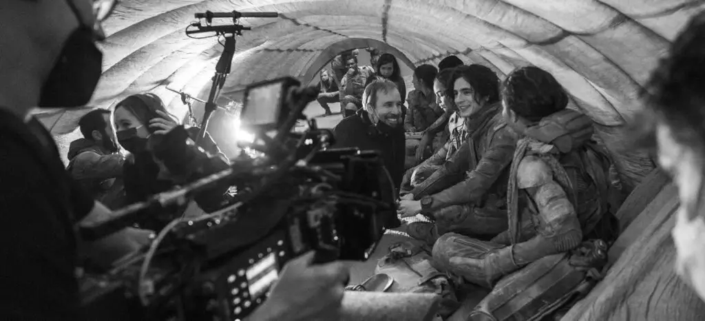 Behind-the-scenes shot from 'Dune: Part Two' featuring director Denis Villeneuve and stars Timothée Chalamet and Zendaya.